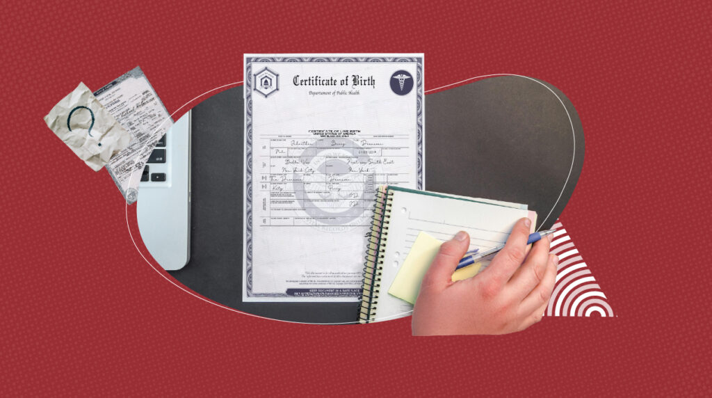 A birth certificate on a table along with a hand on a notebook holding a pen and in the corner a computer