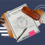 A flat lay composition featuring a U.S. birth certificate labeled “Certificate of Live Birth” placed on a wooden surface. Around it are a pen, a wooden case, a small pink sticky note that says “Translate?”, a crumpled paper with a question mark, and a person’s hand holding a pen as if filling out a document. The background is dark blue with geometric graphic accents.